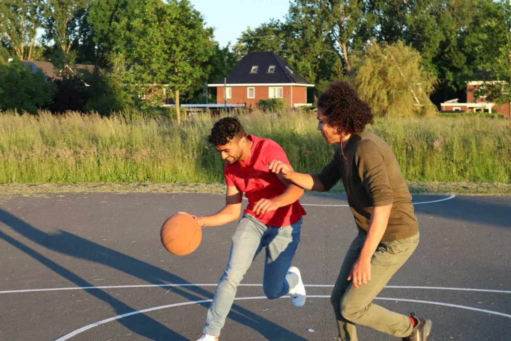 2 jongens spelen basketbal voor een project van de jongeren stichting die maatschappelijke projecten organiseert